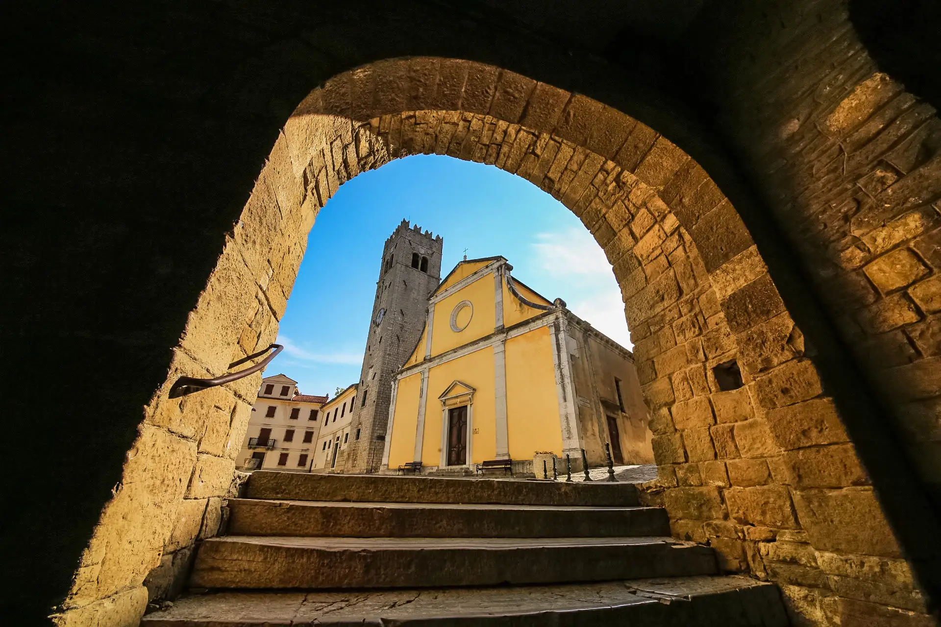 walking under the arches and the view of the yellow church and church tower in the front on the main town square