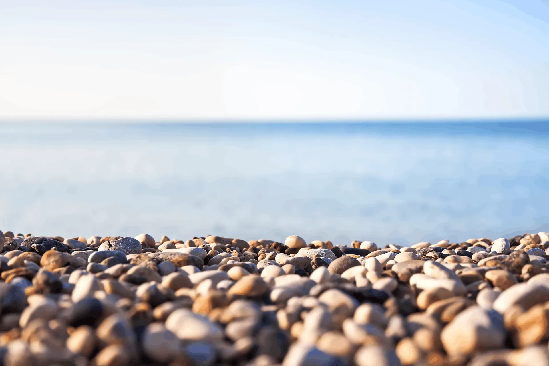 pebble beach with blue sea and blue sky in the background