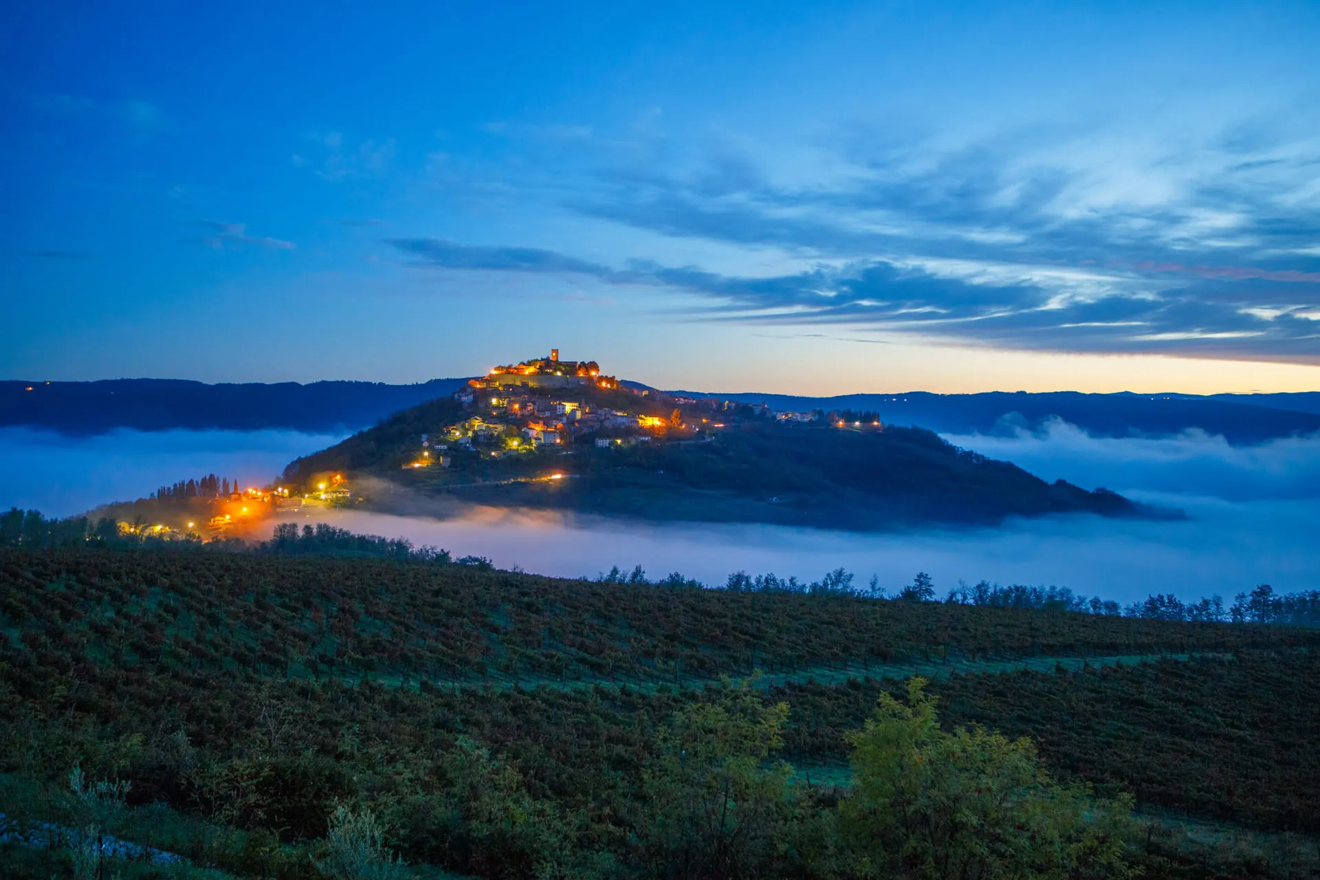 night image of Motovun on the hill wit hthe fog raising up