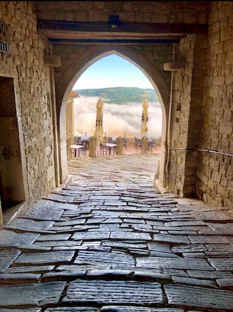 cobblestone street in Motovun under the stone arches with a view of the cafe and hills