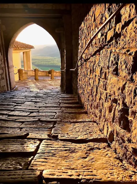 cobblestone street in Motovun with a view of the valley