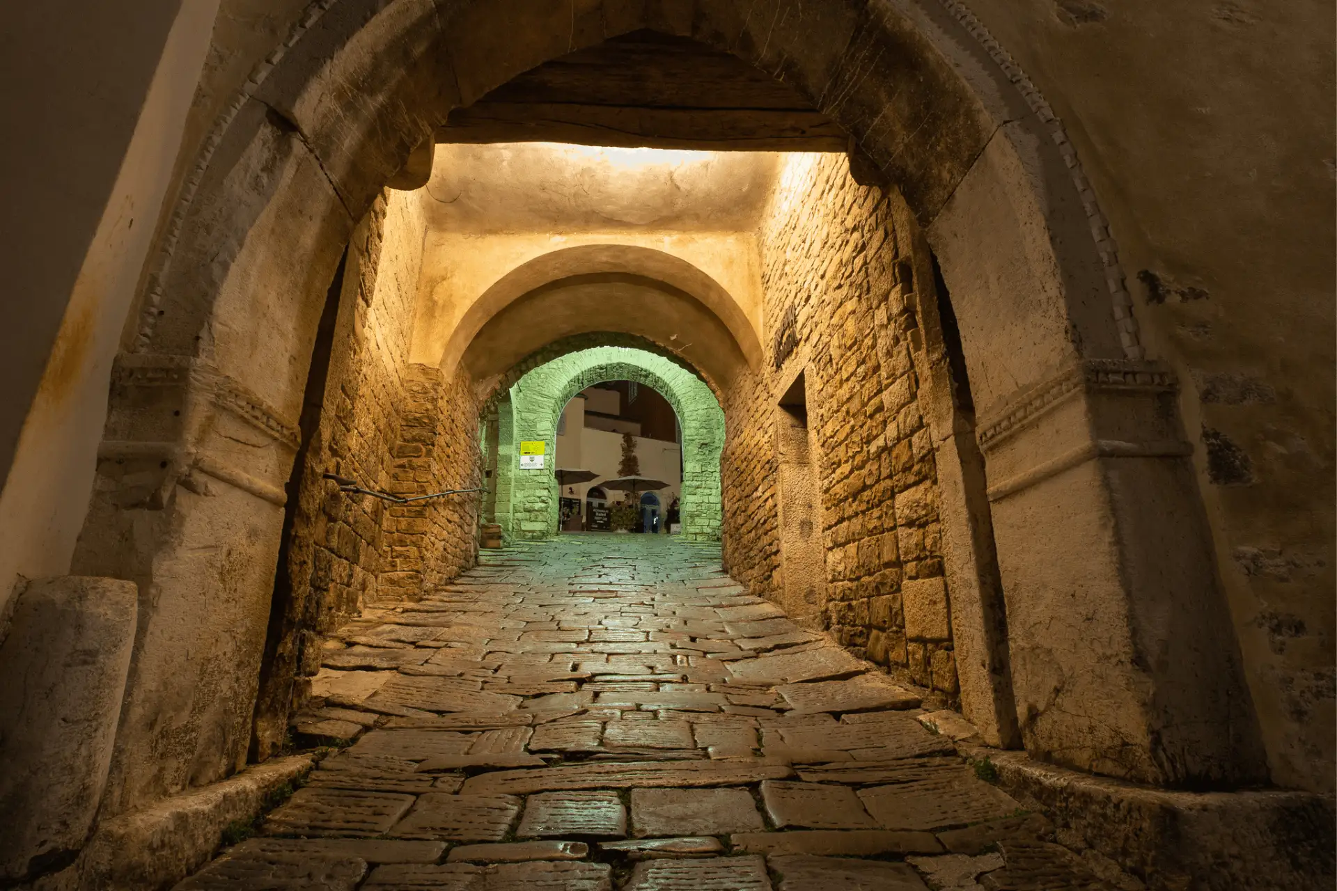night image of a cobblestone street in Motovun under the old stone arches
