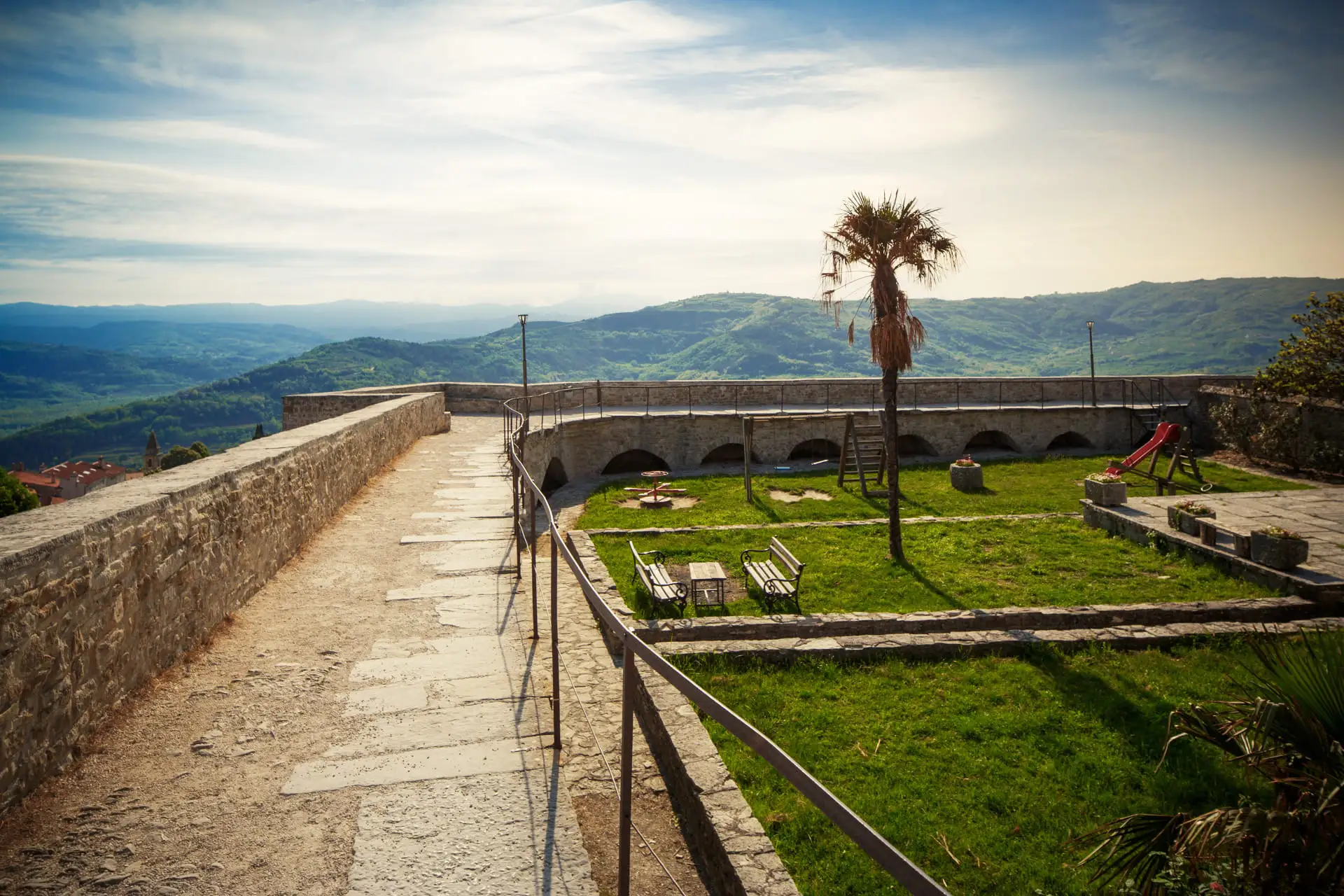 garden inside the walls on the top of the hill where Motovun is located. In the distance there are green hills and forests