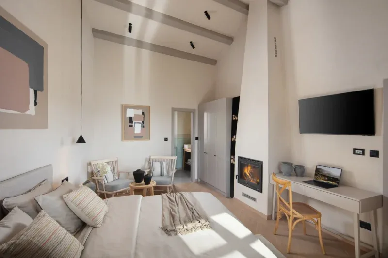 luxury bedroom in villa Motovun with white walls, high ceiling, fire place, tv and a large bed